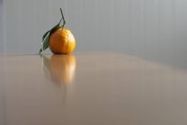 Mandarin orange jetant réflexion sur la table dans une pièce vide — Photo de stock