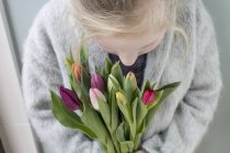 Primer plano de la niña sosteniendo un montón de tulipanes - foto de stock