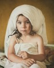 Portrait of a girl sitting on bed wrapped in towels after bath — Stock Photo