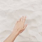 Крупный план руки тянется к песку на пляже, обрезанное изображение — стоковое фото
