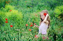 Chica caminando por el campo de amapola floreciente - foto de stock