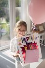 Girl holding birthday present and a balloon — Stock Photo