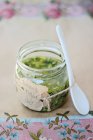Homemade pesto sauce in glass jar and porcelain spoon — Stock Photo