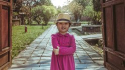 Chica con sombrero de pie con los brazos cruzados en el camino - foto de stock