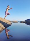 Хлопчик стрибає зі скелі в море з блакитним небом на фоні — стокове фото