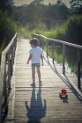 Junge zieht Spielzeug-LKW über Holzbrücke — Stockfoto