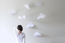 Rear view of woman holding stick behind head with pieces of paper flying around — Stock Photo