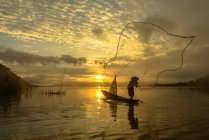 Silhouette d'un homme lançant un filet de pêche, Lac Bangpra, Thaïlande — Photo de stock