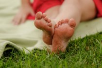 Image recadrée de fille pieds sur herbe verte, gros plan — Photo de stock