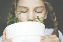 Girl smelling mint plant in a plant pot — Stock Photo