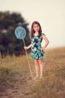 Девушка держит сетку бабочки в поле — стоковое фото