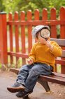 Хлопчик сидить на лавці тримає збільшувальний стакан — стокове фото