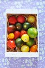 Draufsicht auf Schachtel mit bunten Kirschtomaten, buntem Hintergrund — Stockfoto