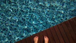 Cropped image of female feet by a swimming pool — Stock Photo