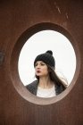 Mujer joven mirando a través de un agujero circular - foto de stock