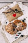 Croissants, blueberries and surprise envelope on fabric on wooden surface — Stock Photo
