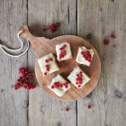 Overhead view of carrot cake with redcurrants on a chopping board — Stock Photo