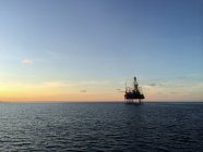 Silueta de una plataforma en alta mar durante la puesta del sol - foto de stock