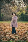 Portrait of a girl looking thoughtful, standing in autumn leaves — Stock Photo