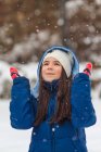 Chica feliz con las manos en el aire jugando en la nieve - foto de stock