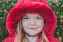 Портрет дівчини в червоному пальто дивиться на камеру — стокове фото