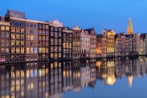 Живописный вид на ряд домов вдоль канала в сумерках, Амстердам, Голландия — стоковое фото