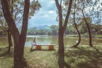 Visão traseira de uma mulher sentada no banco perto do lago, Hue, Vietnã — Fotografia de Stock