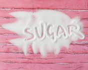 Palavra açúcar escrito em açúcar na mesa de madeira rosa — Fotografia de Stock
