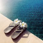 Flip flops with flowers at the edge of a swimming pool — Stock Photo