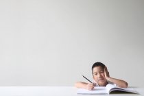 Мальчик сидит с блокнотом, учится на белом фоне — стоковое фото