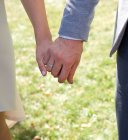 Cropped image of groom and bride holding hands — Stock Photo