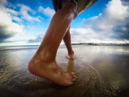 Sezione bassa di un ragazzo che cammina sulla spiaggia — Foto stock