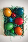 Vista elevada da cesta com ovos de páscoa coloridos — Fotografia de Stock