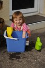 Sonriente niña con las manos en un cubo - foto de stock