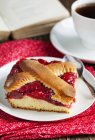 Piece of cherry pie and cup of tea on red folded tablecloth — Stock Photo