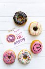 Selection of donuts with multi-colored icing with note — Stock Photo