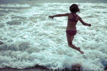 Bambina che corre in mare con le onde — Foto stock
