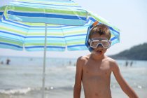 Menino vestindo snorkel e máscara de pé na praia — Fotografia de Stock