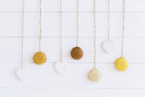 Macaroons hanging on strings against white wall — Stock Photo