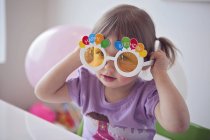 Little girl wearing happy birthday glasses — Stock Photo