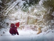 Baby boy playing in snow with a teddy bear — Stock Photo