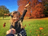 Chica lanzando hojas en el aire en el parque de otoño - foto de stock