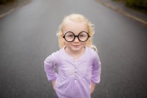 Portrait of a girl wearing silly glasses standing on road — Stock Photo