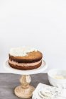 Sponge cake being iced against white wall — Stock Photo