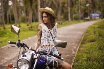Эгги татуированная женщина, сидящая на мотоцикле — стоковое фото