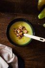 Potato, leek and pear cream soup in bowl on wooden surface — Stock Photo