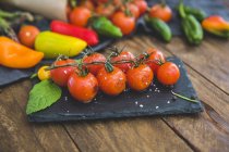 Tomates cherry asados con verduras en mesa de madera - foto de stock