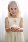 Girl holding a cupcake decorated with daisies — Stock Photo