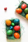 Multicolored Easter eggs on artificial grass in boxes — Stock Photo