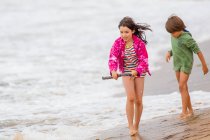 Niño y niña caminando por la playa - foto de stock